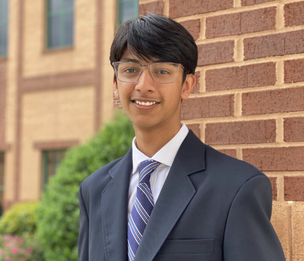 Photograph of Ishaan Agarwal, author of this blog, smiling and standing in front of a brick building.